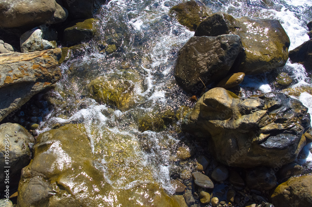 rocky sea shore with pebble beach, waves with foam