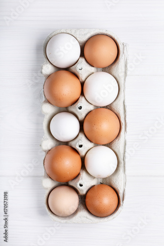 Pack of farm chicken eggs in cardboard container on white.