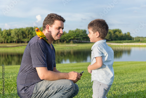 Little boy and father play with bird in the park. © kanchitdon