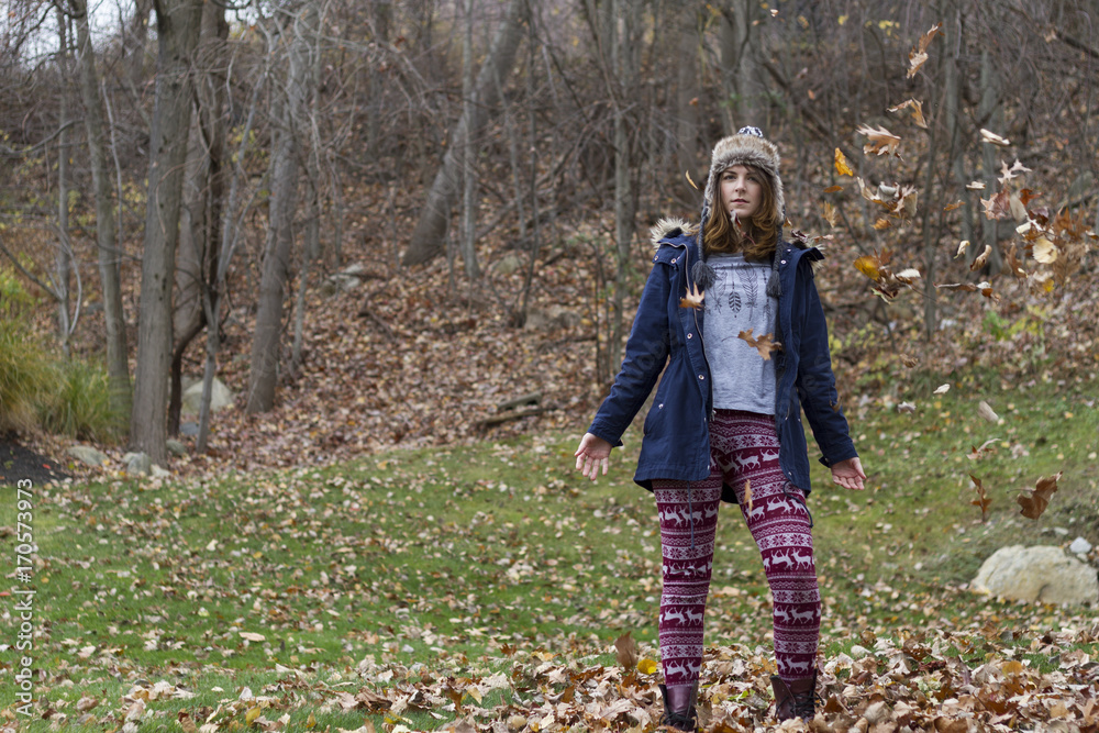 Autumn leaves falling on happy young woman in forest Autumn leaves falling on happy young woman in forest
