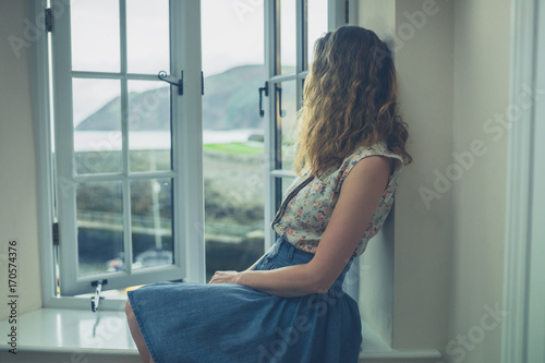 Woman sitting by window of rural home