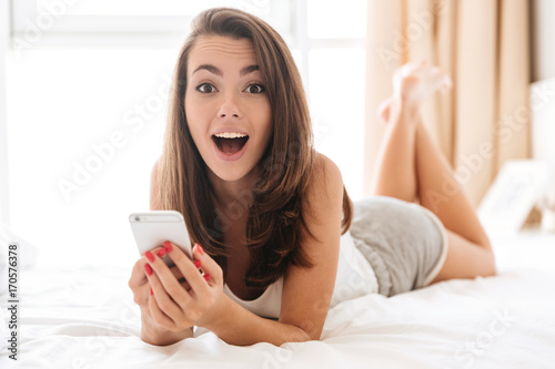 Close up portrait of happy excited woman holding mobile phone