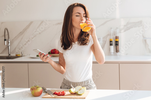 Foto Young joyful woman drinking orange juice