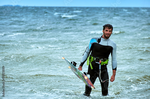 Man riding a kite surfing on the waves in the summer.