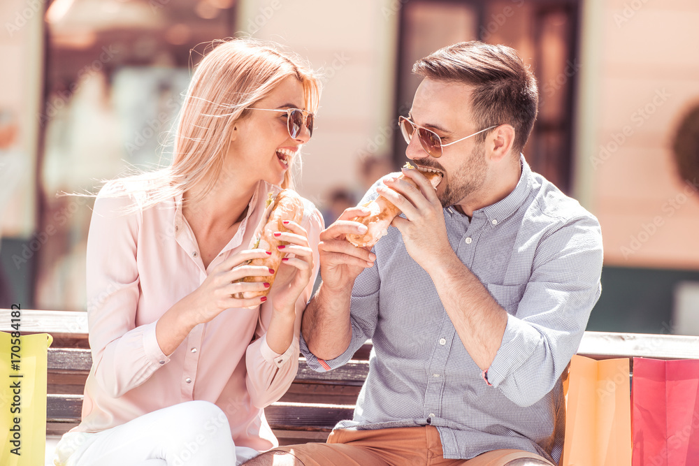 Couple enjoying lunch sitting at bench in city. Couple enjoying lunch sitting at bench in city.
