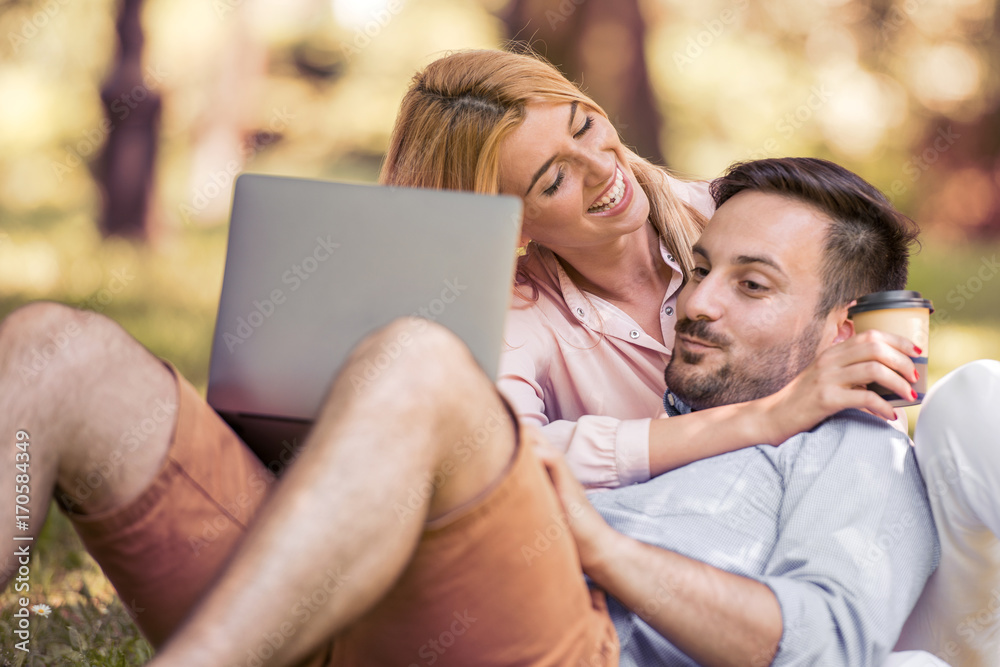 Couple sitting and using laptop at park.