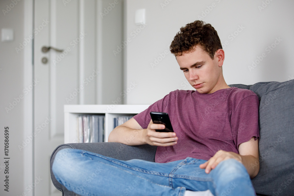 Young man using smartphone on sofa