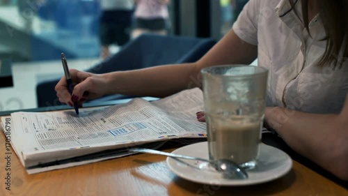 Businesswoman reading newspaper and looking for job in cafe
