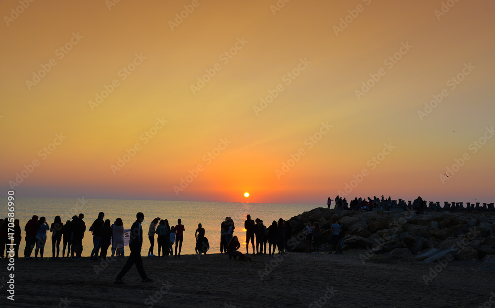 People watching the sunrise on the beach of Costinesti, Romania