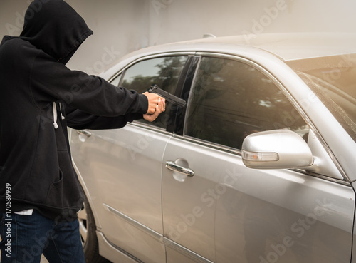 Terrorist bandit thief a car ,pointing a gun at the driver car owner