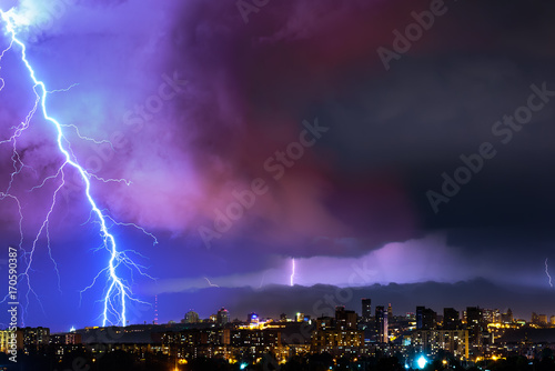 Lightning over the city at the summer storm. Dramatic, breathtaking atmospheric natural phenomenon.