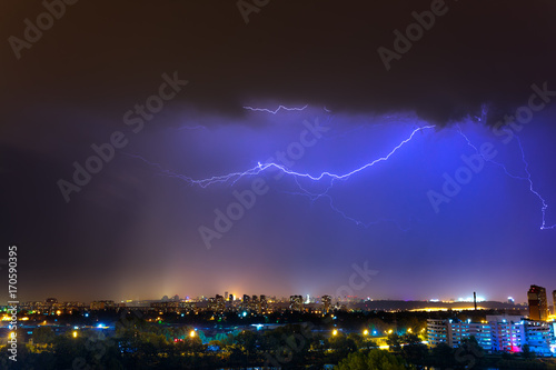Lightning over the city at the summer storm. Dramatic, breathtaking atmospheric natural phenomenon.
