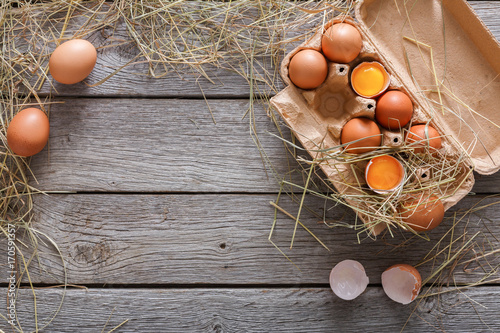 Fresh brown eggs in carton on rustic wood background