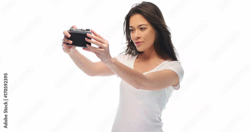 Closeup portrait of pretty young brunette woman in white t-shirt holding retro camera isolated over white background Closeup portrait of pretty young brunette woman in white t-shirt holding retro camera isolated over white background