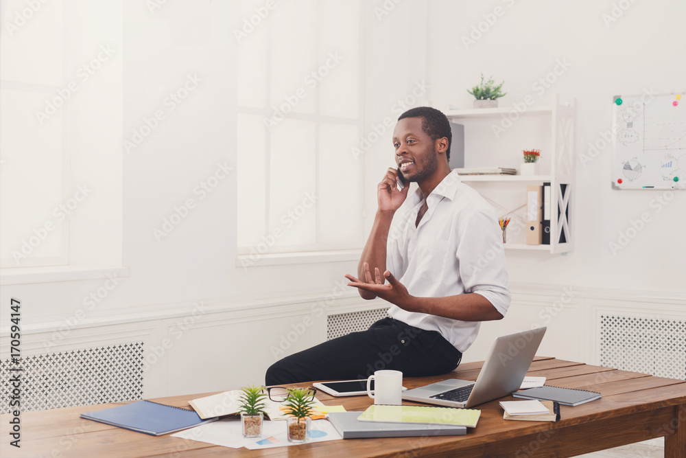 Young black businessman with mobile in modern white office