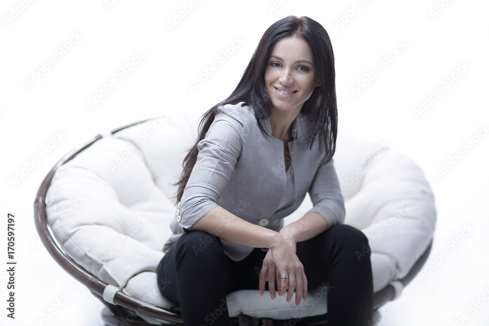 Young woman sitting in a round cozy soft big chair.
