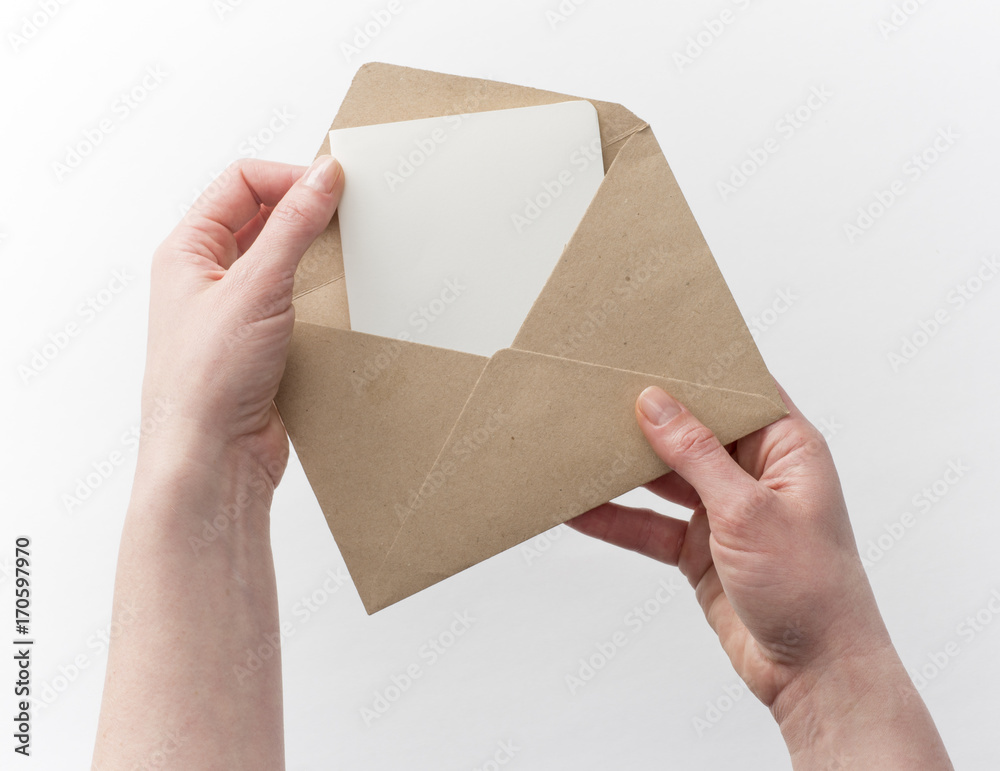 Female hands put the letter in the craft envelope, isolated on white Female hands put the letter in the craft envelope, isolated on white