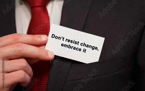 Businessman putting a card with text Dont resist change embrace it in the pocket