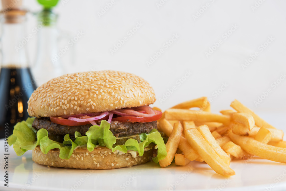 Tasty classical burger with fried potato on white table Tasty classical burger with fried potato on white table