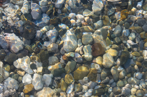 sea pebble beach with multicoloured stones, waves with foam © Wingedbull