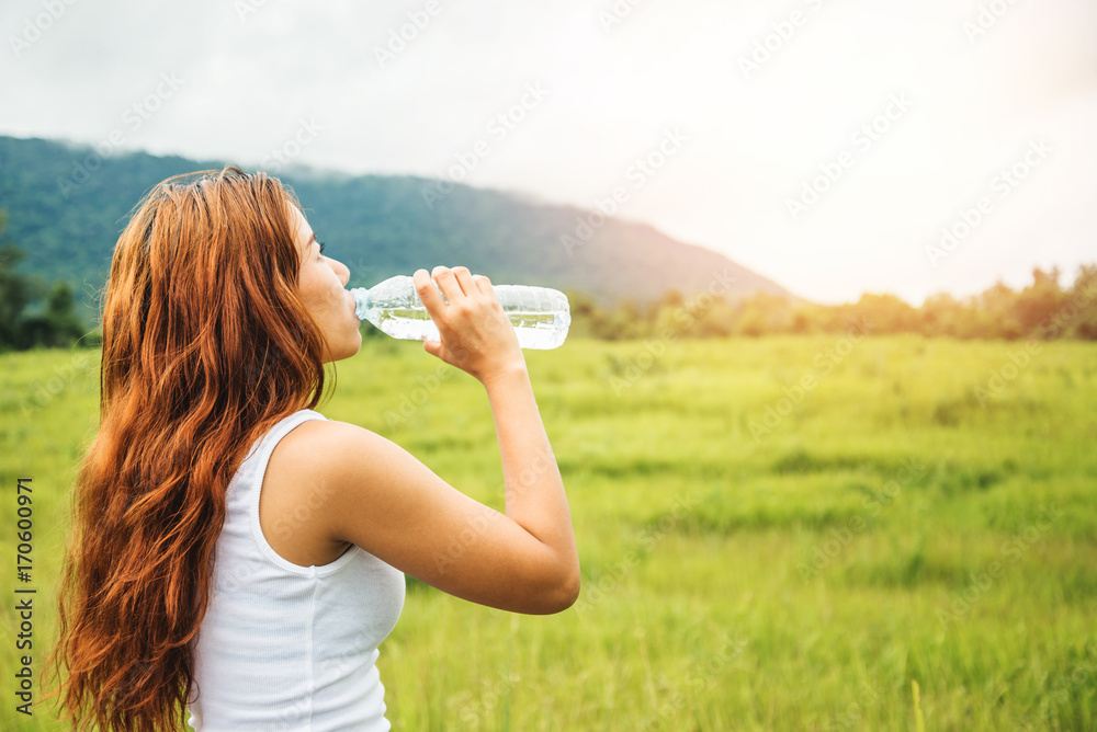 Asian women travel relax in the holiday. Drink Water on a green pasture. Asian women travel relax in the holiday. Drink Water on a green pasture.