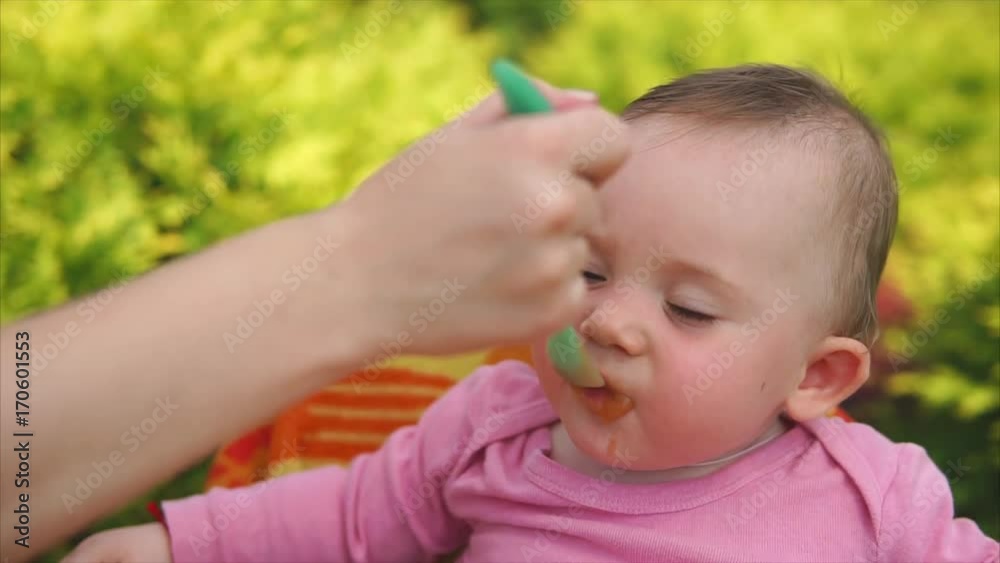 A small and cute child who recently was born eating mashed vegetables from vegetable mashed potatoes, the child eats porridge, some of the food on his face A small and cute child who recently was born eating mashed vegetables from vegetable mashed potatoes, the child eats porridge, some of the food on his face