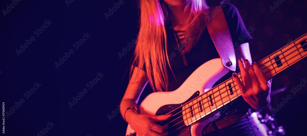 Fototapeta Beautiful female guitarist performing in nightclub