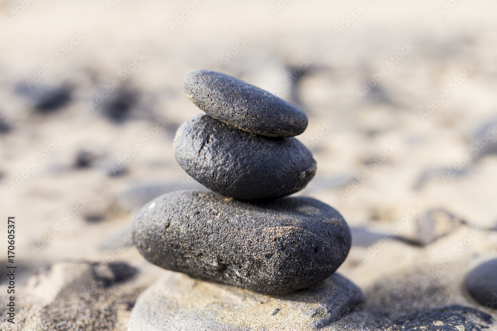 Close up view of a Pyramid from black volcanic stones at the beach. Yellow sand beach in Canary Islands Close up view of a Pyramid from black volcanic stones at the beach. Yellow sand beach in Canary Islands