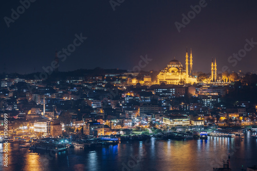 Istanbul sunset panorama - Turkey travel background. Night view on the restaurants at the end of the Galata bridge, Sultanahmet, at sunset with the famous Suleymaniye Mosque in the background