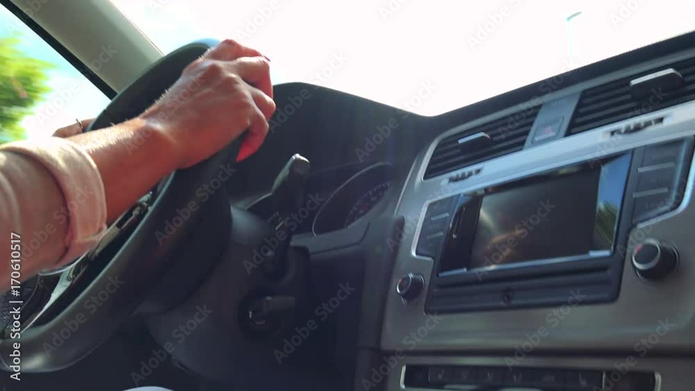 Woman drives a car - closeup of hands on the steering wheel and radio Woman drives a car - closeup of hands on the steering wheel and radio