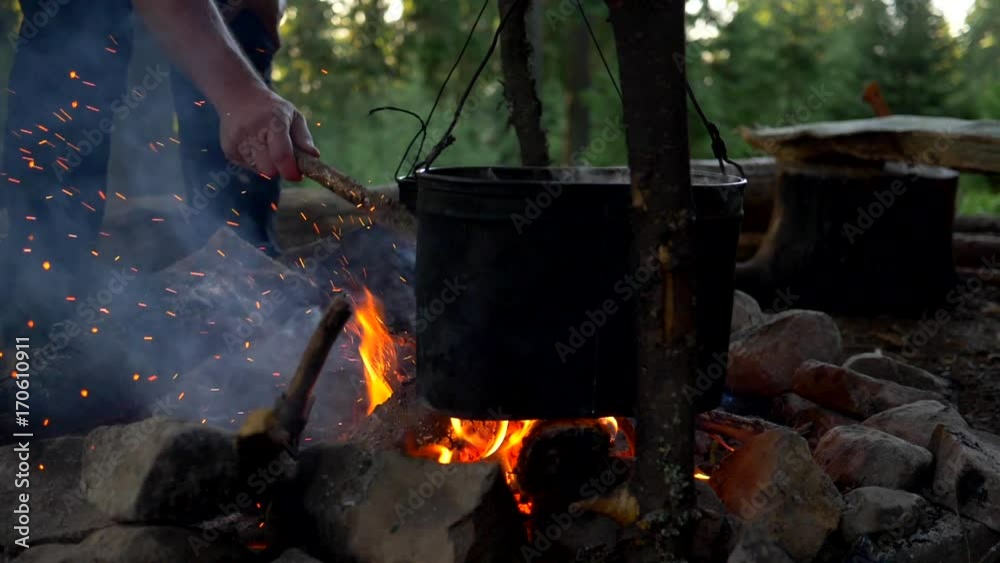 Bonfire cooking. Pot with smoke over camp fire in wild camping Bonfire cooking. Pot with smoke over camp fire in wild camping