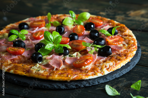 Pizza on a thin dough with olives and fresh basil