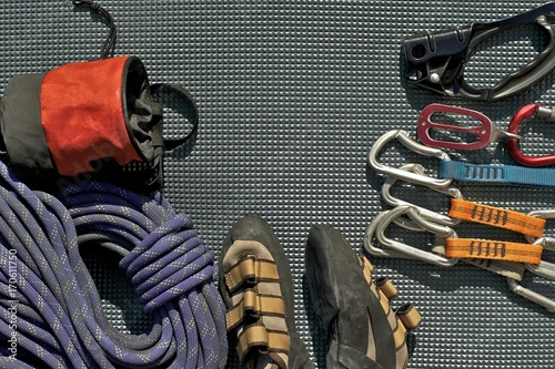 Top view of rock climbing equipment on grey mat. Chalk bag, rope, climbing shoes, belay/rappel device, carabiner and ascender.
Active lifestyle concept. photo