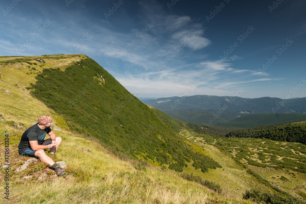 man sitting on rock enjoying a mountain landscape