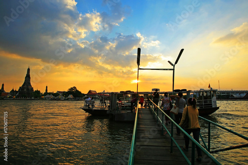 Unidentified people get into ferry to transit across chao phraya river to wat arun, bangkok landmark found before 17th century, at sunset sky on december 9, 2011 in bangkok, thailand