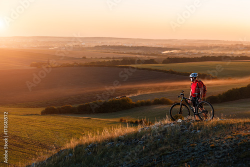 Biker tourist travel on mountain bike. Autumn landscape. Sportsman on bicycle in red jersey and white helmet