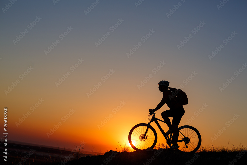 Fototapeta premium Silhouette of a bike tourist on mountain peak.