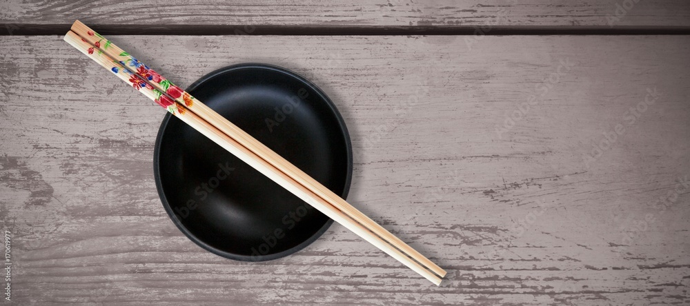 Composite image of close up of chopsticks with black bowl Composite image of close up of chopsticks with black bowl