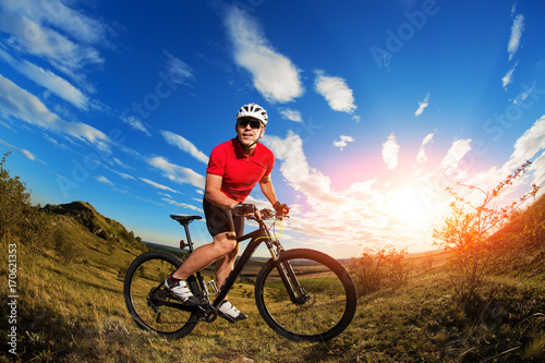 Fototapeta Naklejka Na Ścianę i Meble -  Biker tourist travel on mountain bike. Autumn landscape. Sportsman on bicycle in red jersey and white helmet
