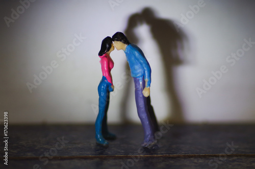 Fototapeta Naklejka Na Ścianę i Meble -  Miniature little people, couple kissing with a shadow behind