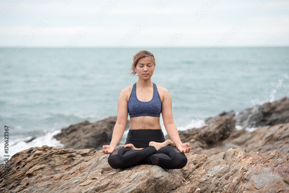 Young asian woman yoga and meditation on the stone at the sea beach, healthy lifestyle and fitness concept. Young asian woman yoga and meditation on the stone at the sea beach, healthy lifestyle and fitness concept.