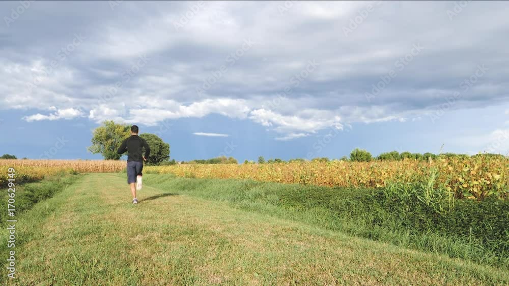 Young man is jogging in the field, slow motion. Young man is jogging in the field, slow motion.