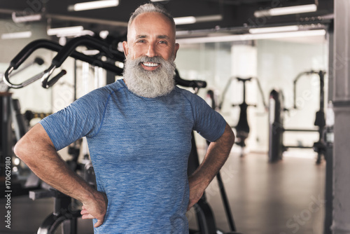 Positive old male with beard is relaxing in sport club
