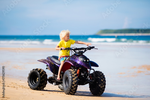 Child on quad bike at beach. All-terrain vehicle.