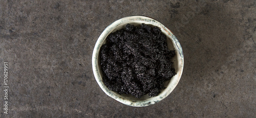 Black sturgeon caviar in a ceramic bowl. Dark background.