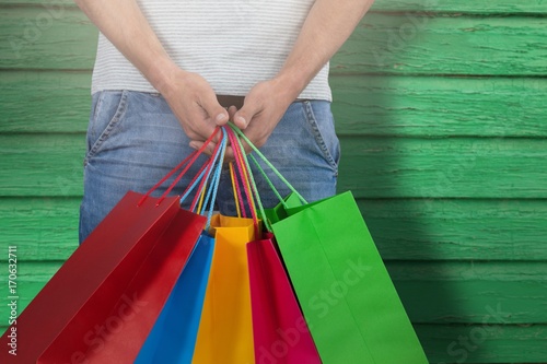 Composite image of midsection of man carrying colorful shopping