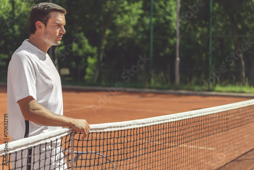 Serious tennis player near net © Yakobchuk Olena