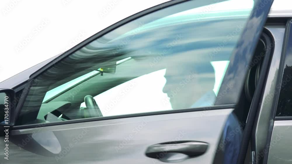 Senior man gets in the car - closeup shot from side - sky in the background 