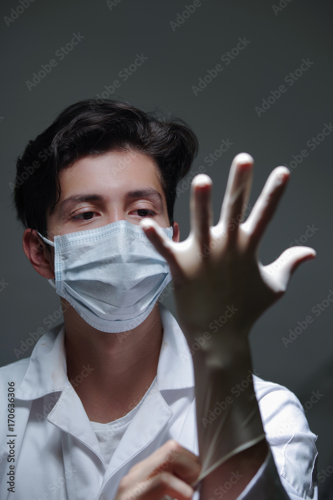 Closeup of a doctor with happy face wearing white surgical mask ina dark background Closeup of a doctor with happy face wearing white surgical mask ina dark background