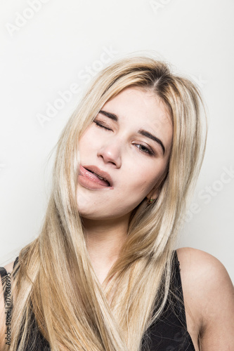 Close-up portrait of a young beautiful blonde girl on a light background. A woman with different emotions on her face.